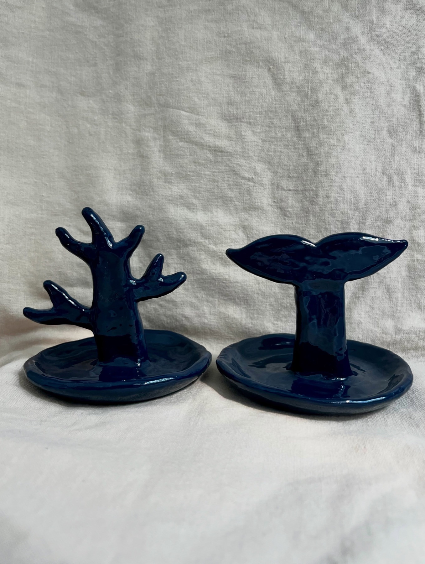 Two deep blue handmade jewelry dishes shaped like coral and a whale tail