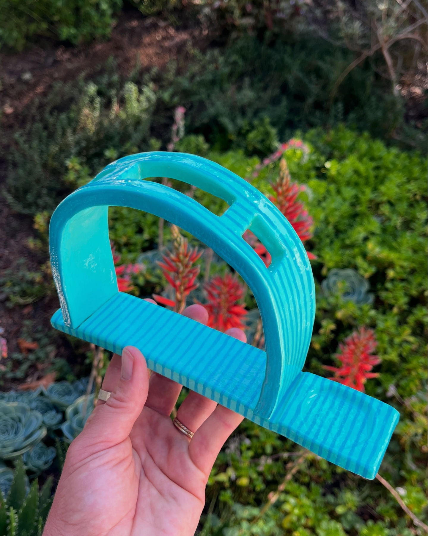 Turquoise handmade ceramic toothbrush holder with a curved handle